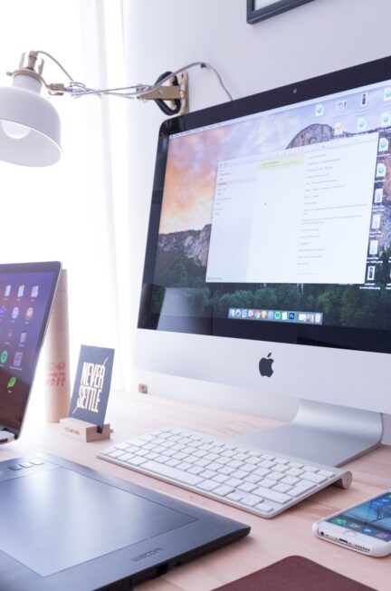 silver iphone near imac on wooden table